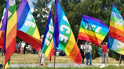 Auf dem Bild sind viele Regenbogen-Fahnen mit der Aufschrift Peace zu sehen.