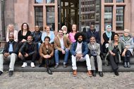 Das Foto zeigt City Walker*innen mit Vertreter*innen der interkulturellen Träger*innenkreise auf den Stufen vor dem Eingang zum Frankfurter Römer sitzend