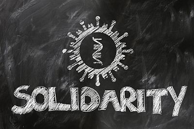 Auf eine Tafel ist mit Kreide das englische Wort für Solidarität geschrieben unter einer symbolhaften Zeichnung des Coronavirus