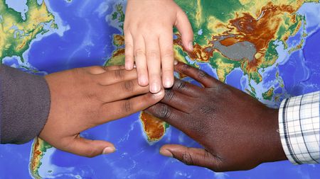 Drei Hände mit unterschiedlichen Hautfarben berühren sich über einer Weltkarte