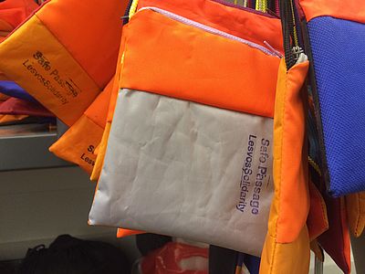 Das Bild zeigt Taschen mit dem Aufdruck „Safe passage“ - Save Passage Bags - aus Rettungswesten von Flüchtlinge, die auf der Flucht über die Ägäis benutzt und zurückgelassen wurden. Sie entstehen in der Nähwerkstatt von Lesvos Solidarity auf Lesbos.